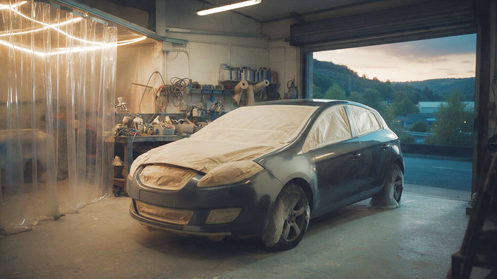 Illustrative image: a hatchback masked up for paintwork in a body repair workshop